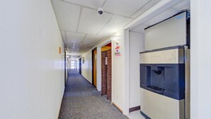 A hotel corridor with a water dispenser, a sign for a restaurant, and a patterned carpet.