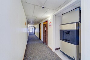 Un pasillo de hotel con dispensador de agua, cámara de seguridad y alfombra estampada.