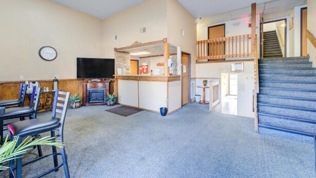 A spacious living area with a fireplace, a dining table, chairs, a TV, and a staircase.
