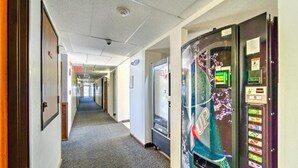 A hotel hallway with a vending machine, an exit sign, and a door.