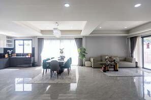 A modern living room with a dining area, a sofa, and a chandelier. - The Ivory ll C26 (Banglamung)