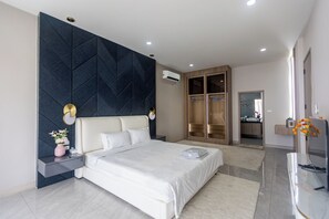 A modern bedroom with a large bed, a dark accent wall, a wardrobe, and a bathroom visible through an open door. - The Ivory ll C26 (Banglamung)