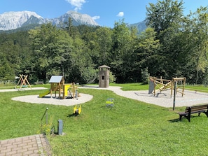 A playground with various play structures, a small shed, and a bench.