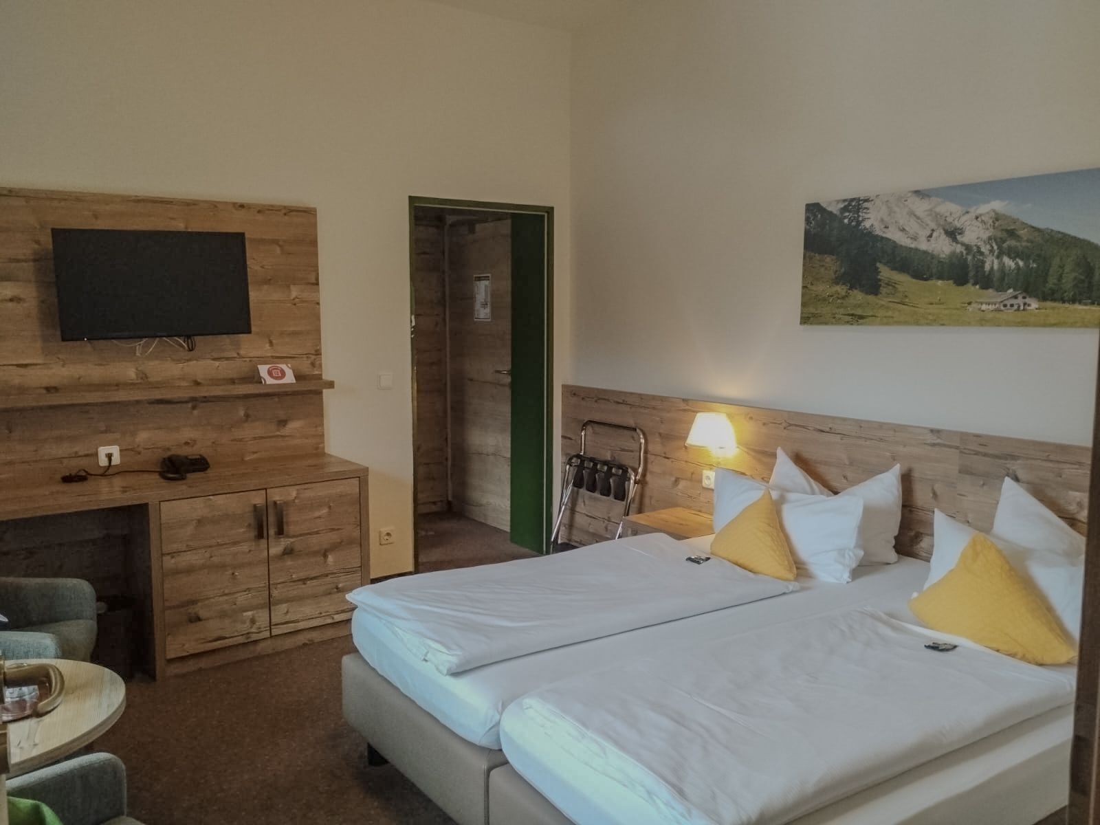 Une chambre d’hôtel avec un lit, un bureau, une chaise, une télévision et un tableau au mur.