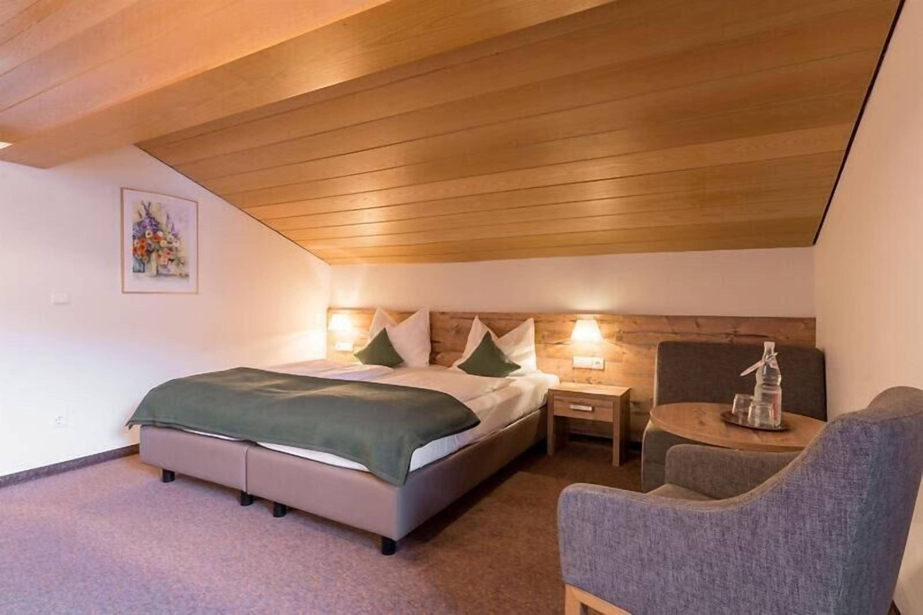 Una camera da letto con un letto, comodini, una sedia e un soffitto in legno.