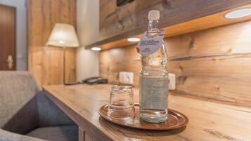 Eine Holztresore mit einer Wasserflasche, einem Glas und einem kleinen Glaskrug auf einer Ablagefläche.