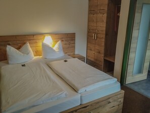 Un lit double avec du linge de lit blanc, une tête de lit en bois et une lampe de chevet.