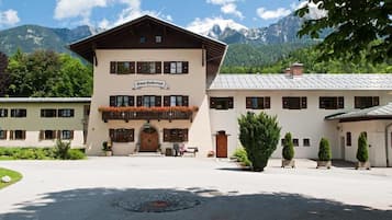Een gebouw met een bord waarop 'Hotel Duberti' staat, een binnenplaats met een rond ontwerp en een berg op de achtergrond.