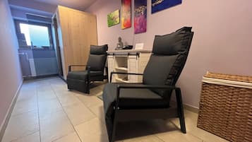 Una habitación con dos sillas negras, un armario de madera y una cesta de mimbre.