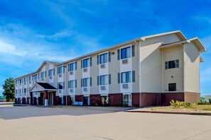 Un hotel de varios pisos con techo plano, entrada cubierta y estacionamiento.