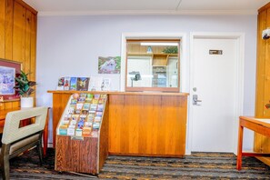 Taulell de recepció amb un tauler d'anuncis, una fusta de mostradora, una porta amb el lema 'Només personal' i una petita planta.