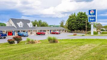 A motel with a signboard, a parking lot, and a building with a sloped roof.