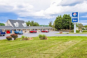 Een Relax Inn motel met een parkeerplaats, een gebouw met een schuin dak en een bord waarop 'vrij' staat.