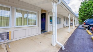 A motel with a covered walkway, a blue door, and a parked car.