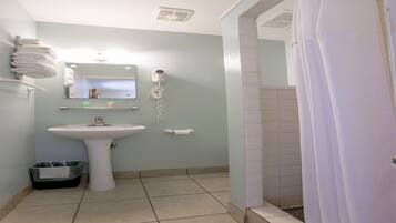 Un baño con lavamanos, espejo, toallero y cortina de ducha.