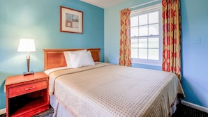 A bedroom with a bed, a nightstand, a lamp, a window with curtains, and a framed picture on the wall. - Queen Bed|Non-Smoking (Natural Bridge, VA)