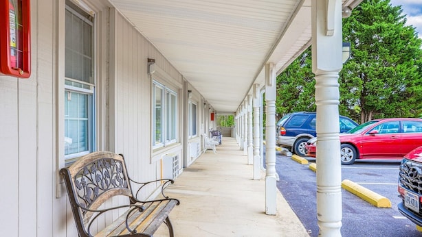 A covered walkway with a bench, a row of windows, and parked cars. - Queen Bed|Non-Smoking (Natural Bridge, VA)