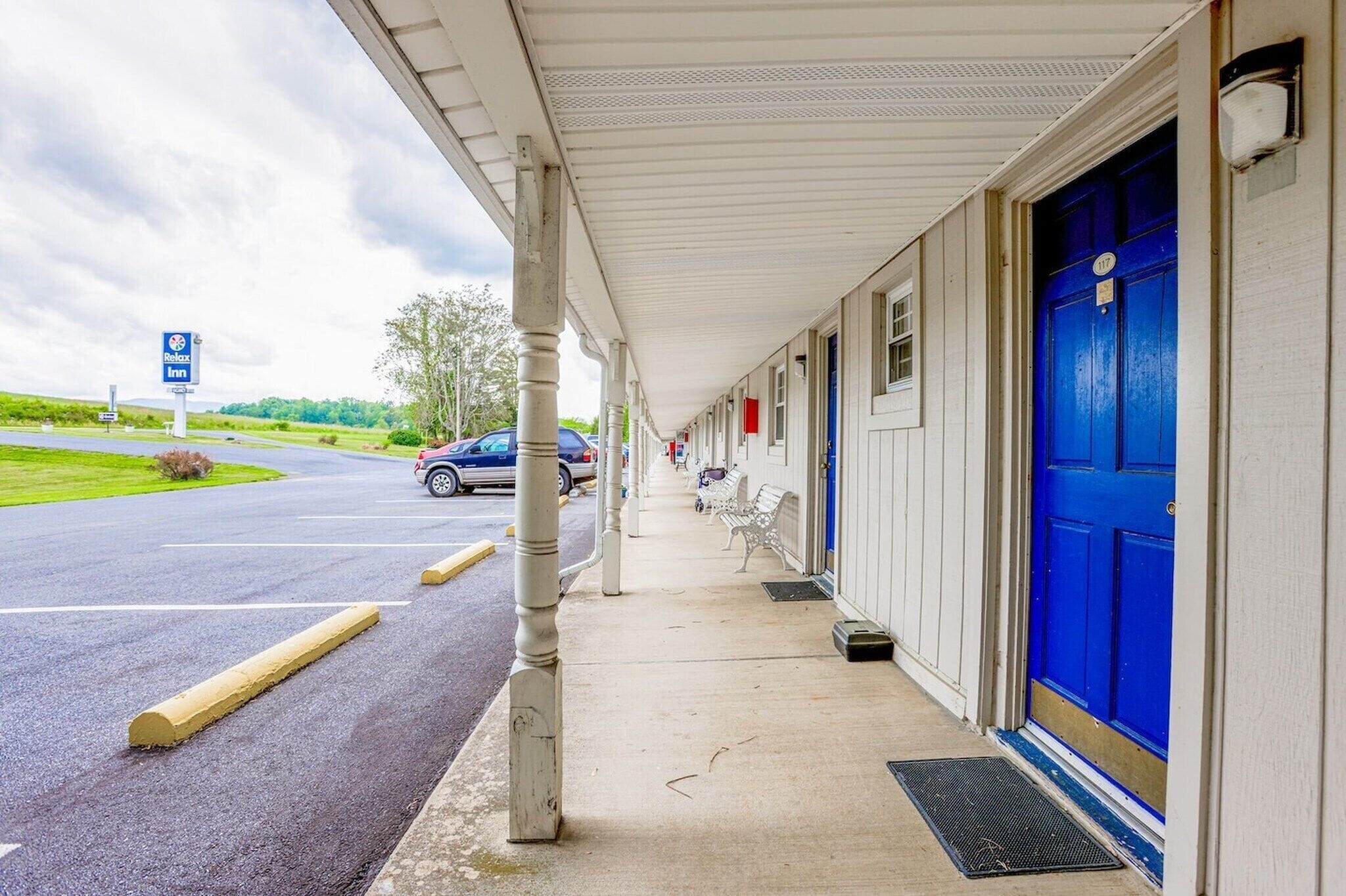 A motel with a covered walkway, a blue door, and a parking lot.