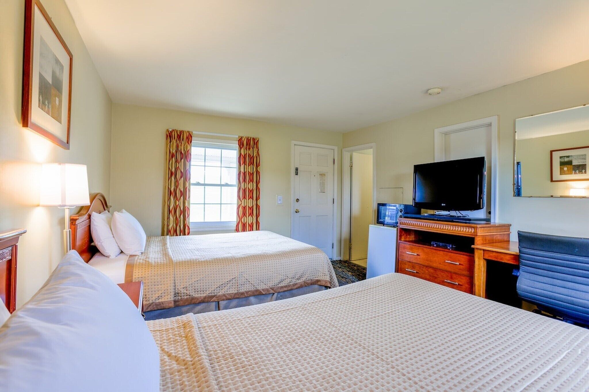 Une chambre d’hôtel avec deux lits, une télévision, un bureau et une commode.