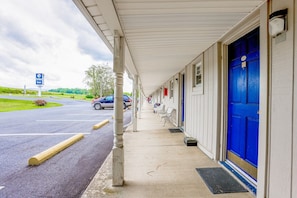 A motel with a covered walkway, a blue door, and a parking lot.