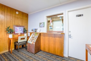 A reception desk with a wooden finish, a chair, a small plant, and a framed picture on the wall.