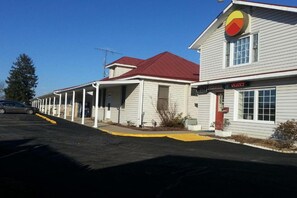 Eine Reihe einstöckiger Gebäude mit rotem Dach, einem Schild mit freien Zimmern und einem Parkplatz.
