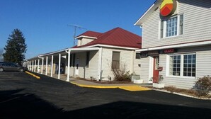 A row of single-story buildings with a red roof, a sign indicating vacancy, and a parking lot.