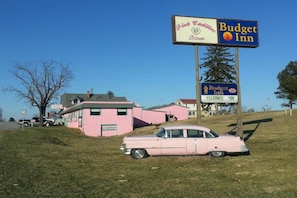 Een roze gebouw met een bord voor Pink Cadillacs en Budget Inn.