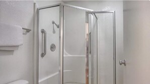 Un box de ducha con paredes de vidrio, un perchero, y una puerta con manija.