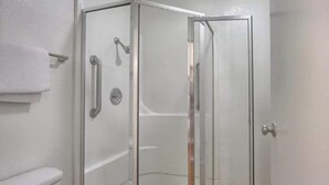 A glass-enclosed shower stall with a white wall, a towel rack, and a door with a handle. - Queen Bed|Non-Smoking (New Cumberland, PA)