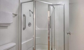 Cabina de ducha con paredes de vidrio y un inodoro a la izquierda.