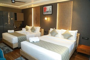 Habitación de hotel con dos camas, minibar, zona de estar y un cuadro en la pared.
