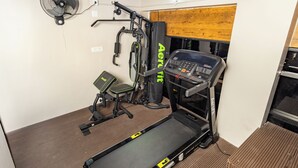Un gimnasio pequeño y funcional con cinta de correr, banco de pesas y equipo de ejercicio.