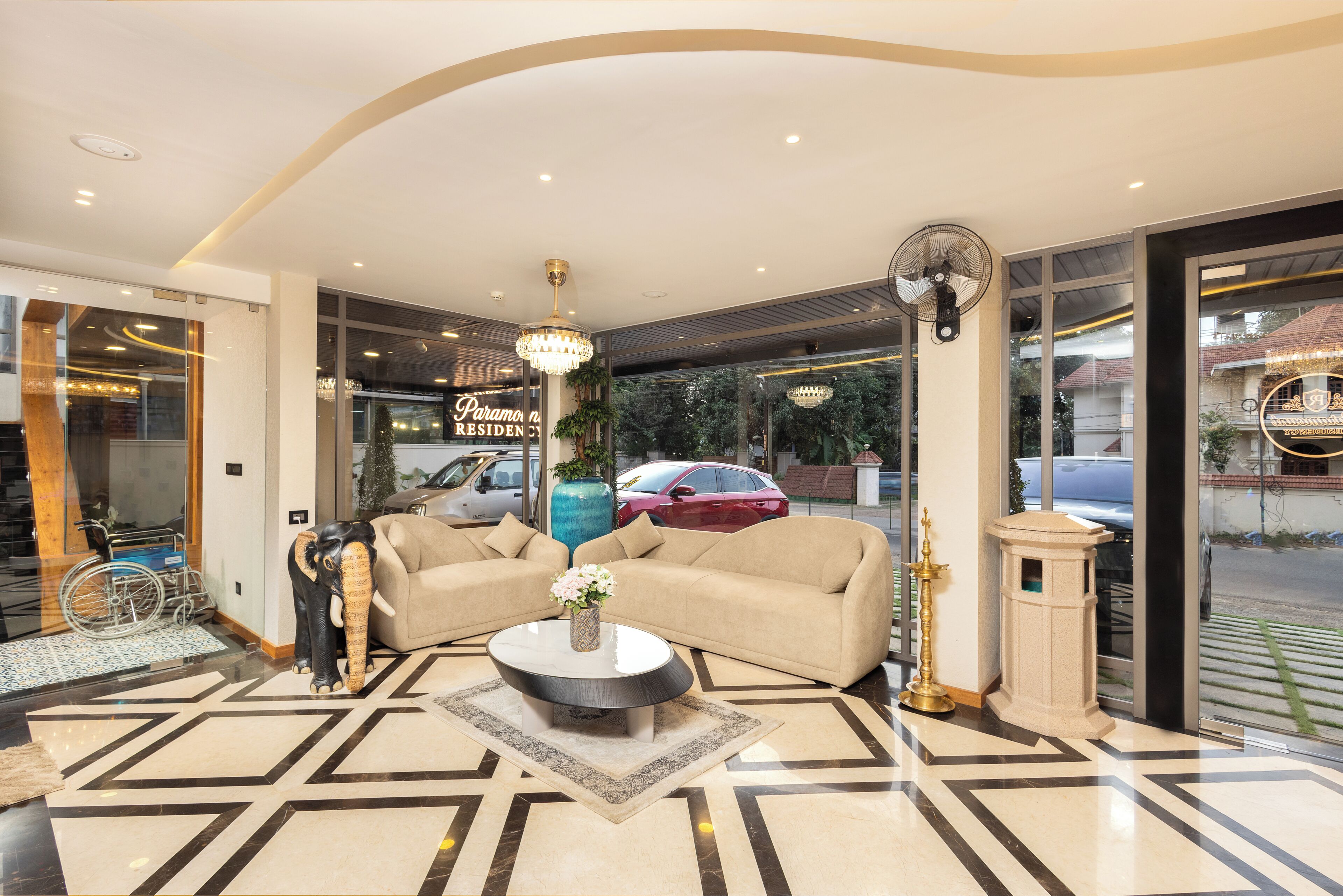A modern lobby with a chandelier, sofas, a coffee table, and a large vase with flowers.
