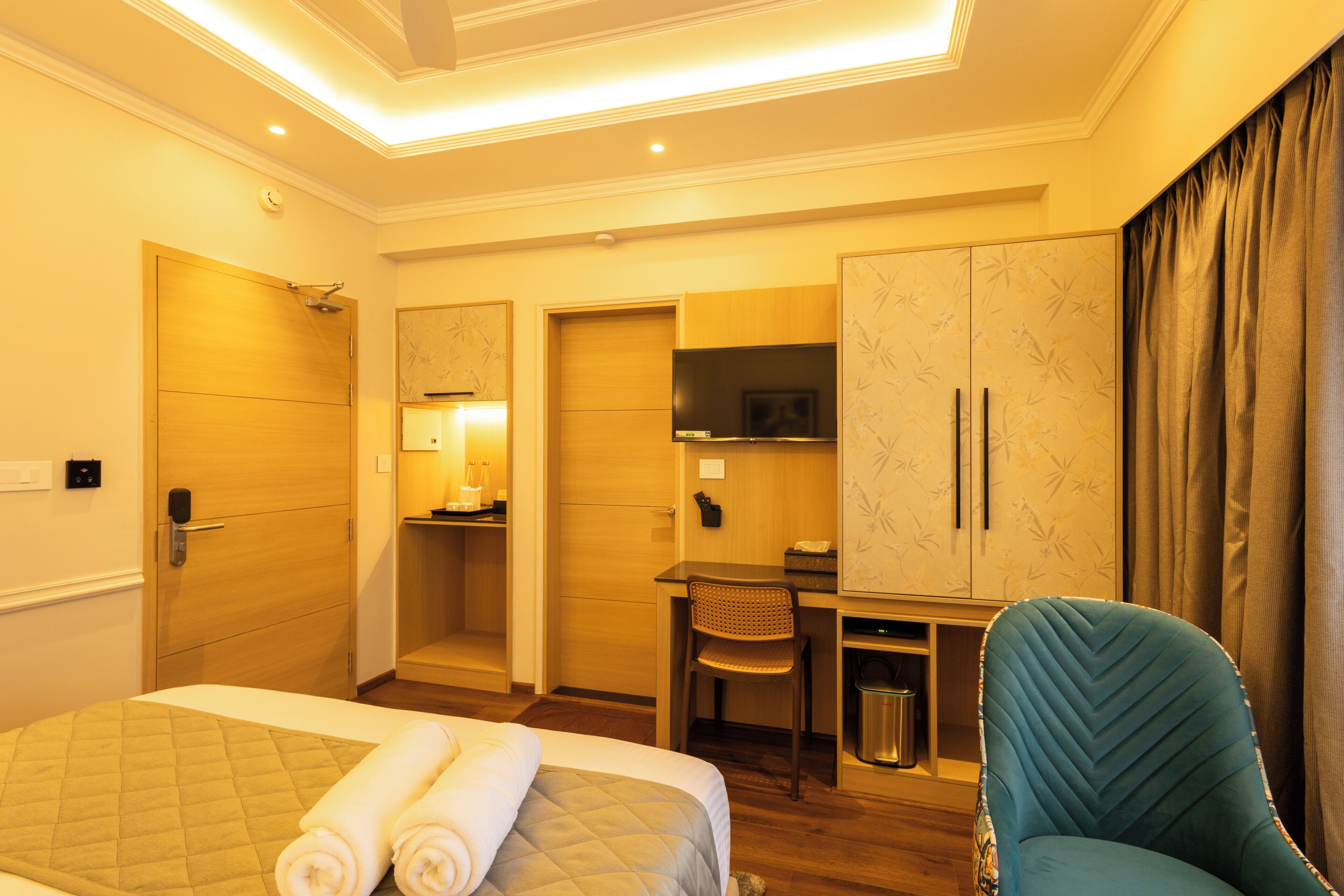 A hotel room with a bed, a desk, a chair, and a wardrobe.