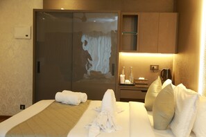 Una habitación de hotel con cama, separador de vidrio, mesita de noche, lámpara y teléfono montado en la pared.