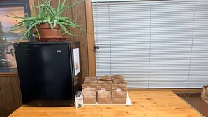 A wooden counter with a black refrigerator, a potted plant, and several paper bags.