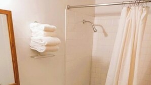 A bathroom with a toilet, sink, shower, and a towel rack.