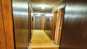 Ein Hotelkorridor mit Holzwänden, Teppichböden und Türen zu Zimmern.
