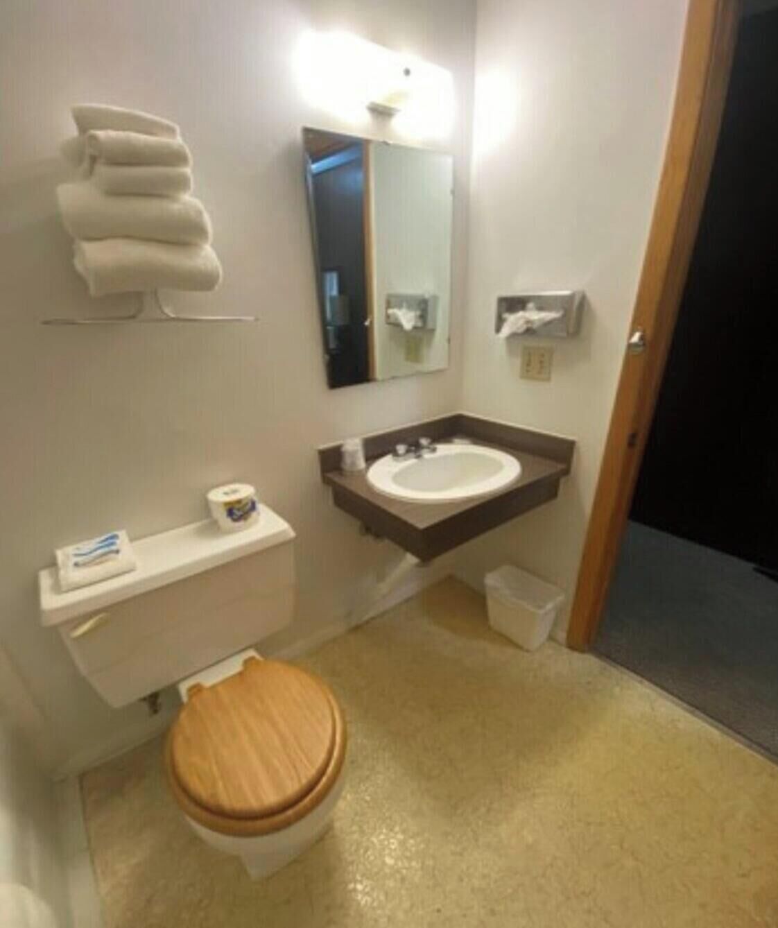 A small bathroom with a toilet, sink, and mirror.