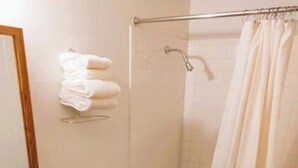 A bathroom with a toilet, sink, shower, and a towel rack. - 2 Full Beds with 1 Twin Bed & Rollaway (International Falls)