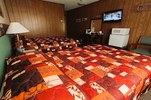 A hotel room with a large bed, a desk, a television, and a microwave.