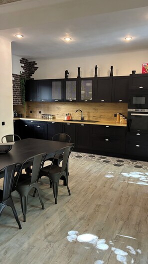 Eine moderne Küche mit dunklen Schränken, einer Holzarbeitsplatte und einem Essbereich mit Tisch und Stühlen.