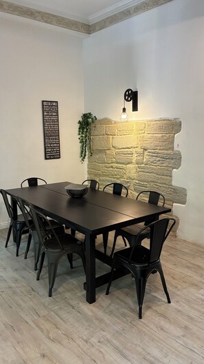 Ein Essbereich mit einer Wand aus Stein, einem Tisch mit Stühlen und einer Wandleuchte.