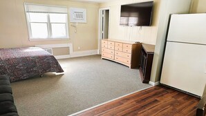 Ein Schlafzimmer mit Bett, Kommode, Fernseher und Kühlschrank.