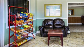 Un salon avec un canapé en cuir, une table basse et un chariot rempli de chips.