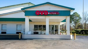 Un hôtel reconnaissable à son panneau bien visible indiquant « OYO HOTEL », doté d’une entrée abritée et d’un parking.