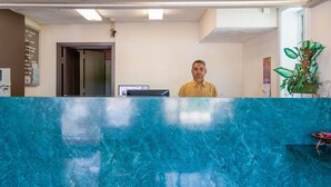 Un mostrador de recepción con encimera de mármol azul, una computadora y una planta.