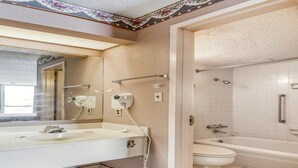 Un baño con lavamanos, espejo, secador de pelo y zona de ducha.