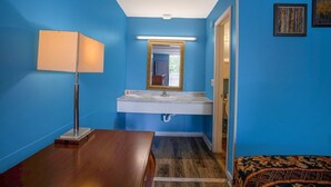 Ein Badezimmer mit blauen Wänden, einem weißen Waschbecken, einem Spiegel, einer Lampe und einem gemusterten Teppich.